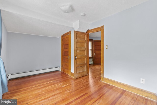 additional living space featuring a baseboard heating unit and wood-type flooring