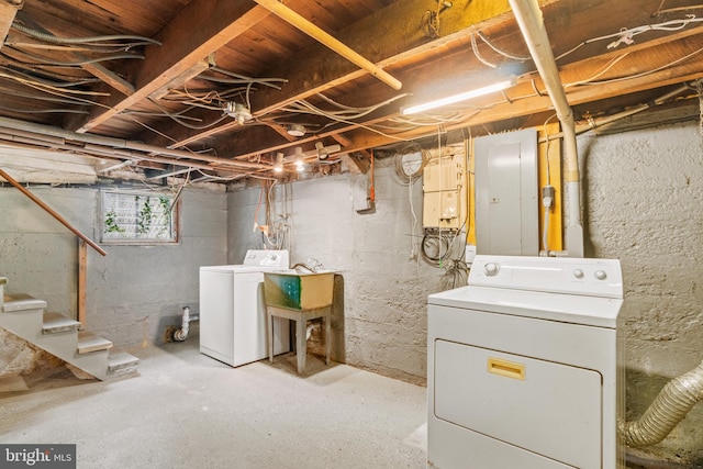 basement with sink, washing machine and clothes dryer, and electric panel