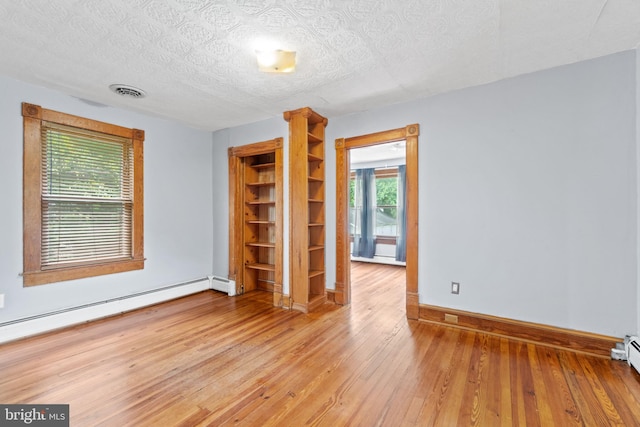 spare room featuring a baseboard radiator, hardwood / wood-style flooring, and a textured ceiling