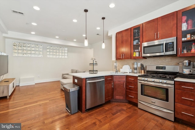 kitchen featuring backsplash, wood-type flooring, appliances with stainless steel finishes, and sink