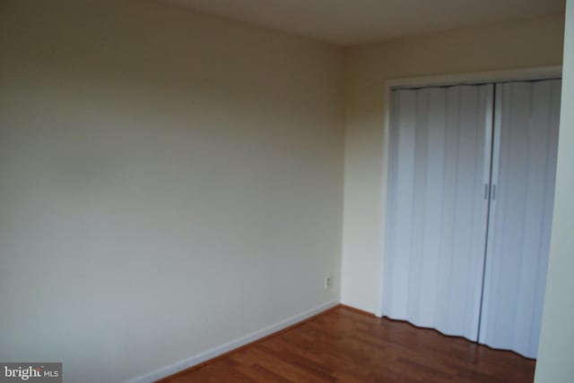 unfurnished bedroom featuring dark wood-type flooring and a closet