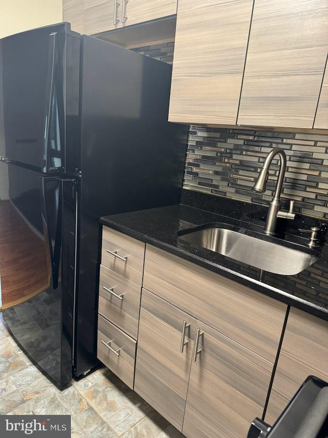 kitchen featuring tasteful backsplash, dark stone counters, and sink