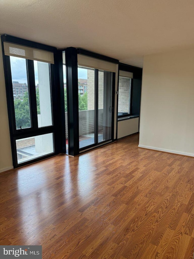 spare room featuring hardwood / wood-style flooring, a wealth of natural light, and a textured ceiling