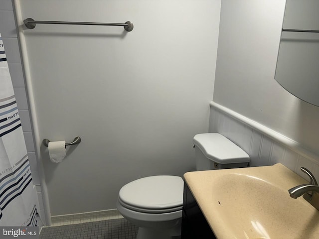 bathroom with toilet, sink, and tile patterned flooring