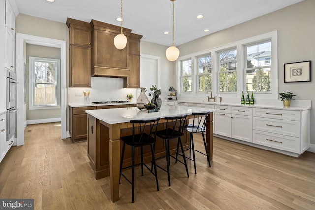 kitchen featuring decorative light fixtures, a kitchen island, plenty of natural light, and light hardwood / wood-style floors