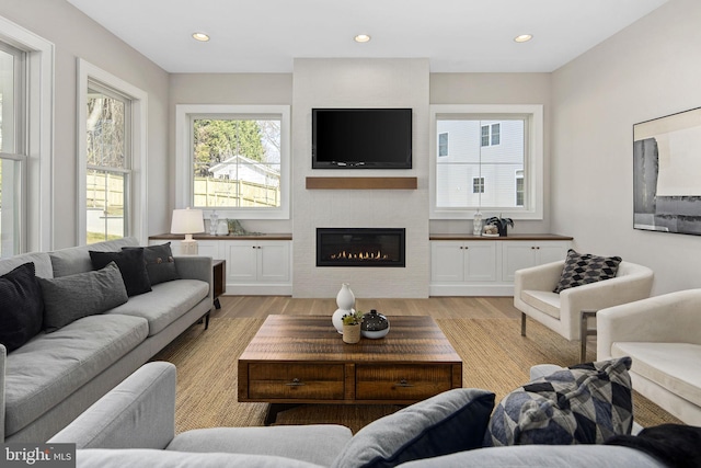 living room featuring light wood-type flooring and a large fireplace