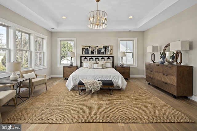 bedroom featuring a raised ceiling and light wood-type flooring