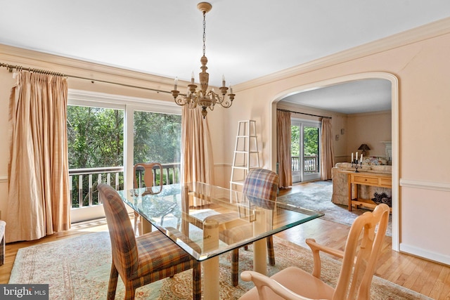 dining room with ornamental molding, light wood-type flooring, and a notable chandelier