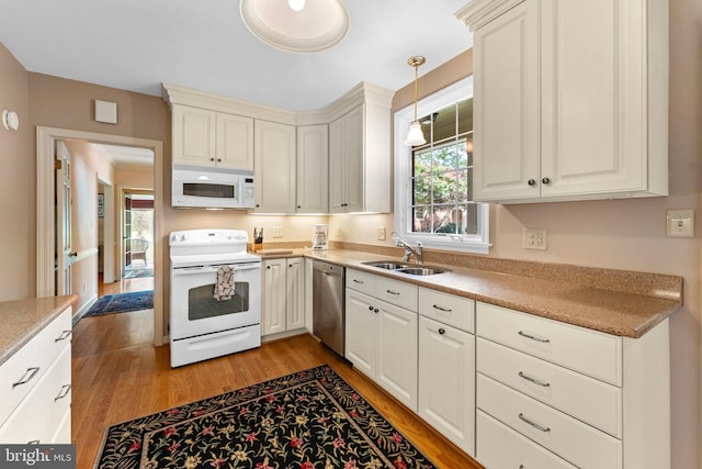 kitchen featuring sink, hanging light fixtures, white appliances, and light wood-type flooring