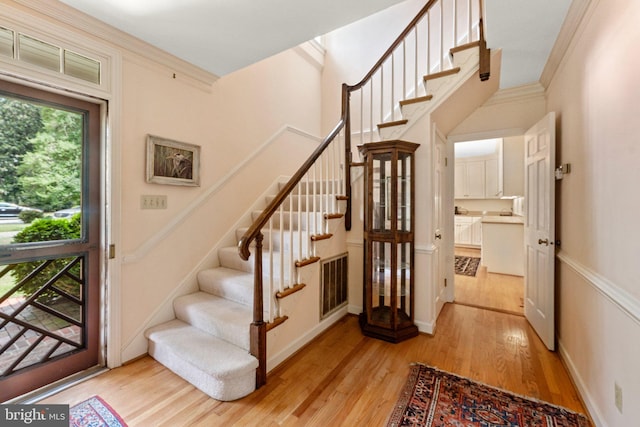 staircase featuring ornamental molding and light wood-type flooring