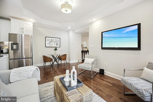 living room featuring dark hardwood / wood-style floors and a tray ceiling