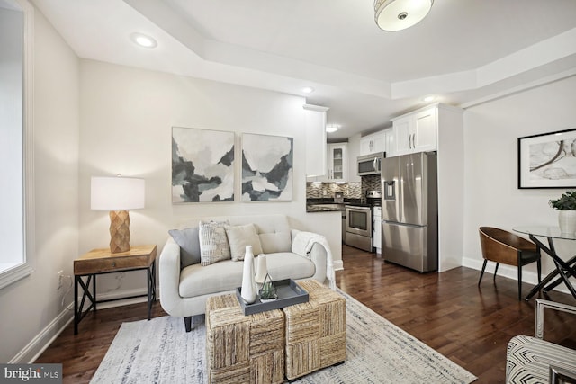 living room featuring a tray ceiling and dark wood-type flooring