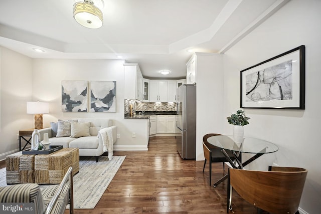 living room with a tray ceiling and dark hardwood / wood-style floors