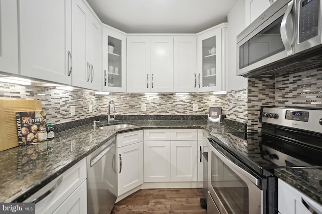 kitchen featuring dark stone countertops, stainless steel appliances, sink, and white cabinets