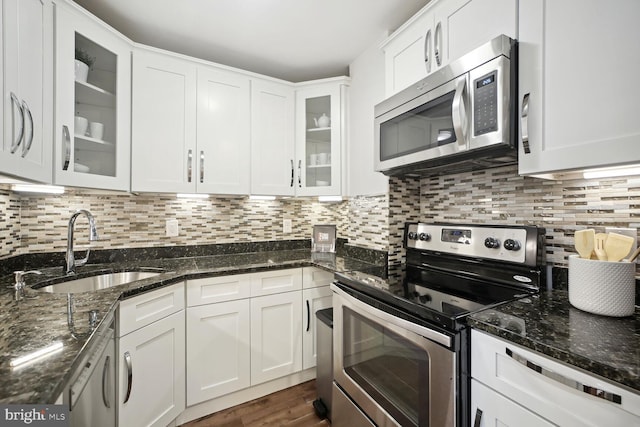 kitchen with sink, stainless steel appliances, white cabinets, decorative backsplash, and dark stone counters