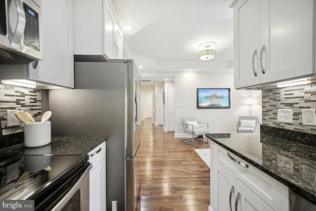 kitchen featuring white cabinetry, light hardwood / wood-style flooring, and dark stone countertops