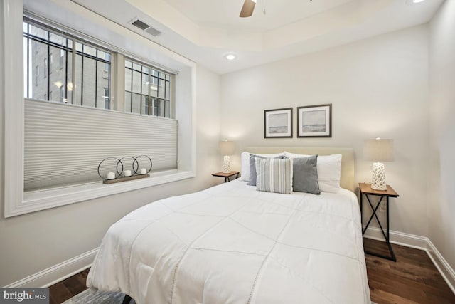 bedroom featuring dark wood-type flooring, ceiling fan, and a raised ceiling