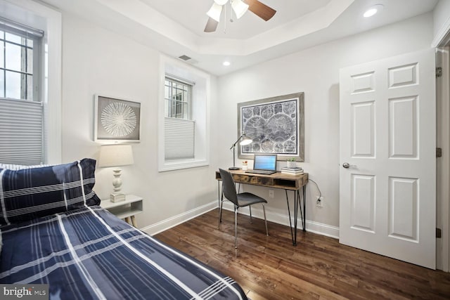 bedroom with dark hardwood / wood-style flooring and a tray ceiling