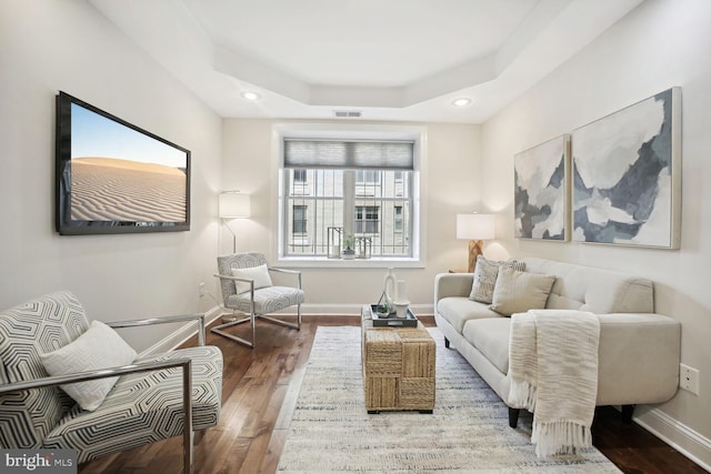 living room with hardwood / wood-style floors and a tray ceiling