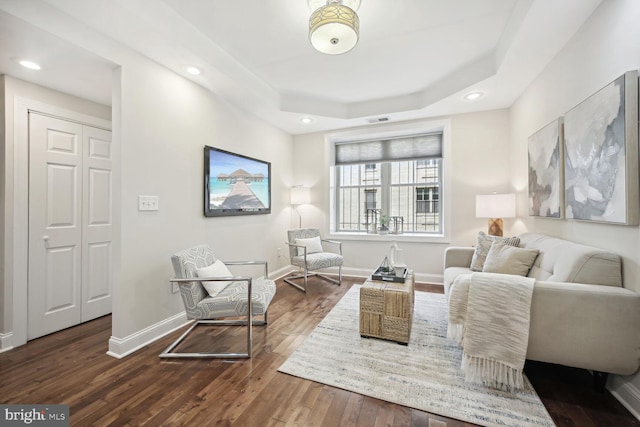 living area featuring a raised ceiling and hardwood / wood-style floors