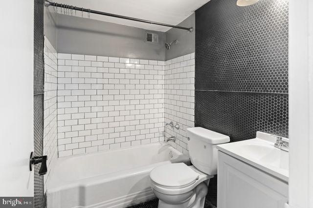 full bathroom featuring toilet, vanity, and tiled shower / bath