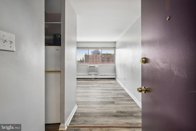 hallway with a baseboard heating unit and light wood-type flooring