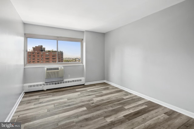 empty room featuring an AC wall unit, a baseboard heating unit, and wood-type flooring