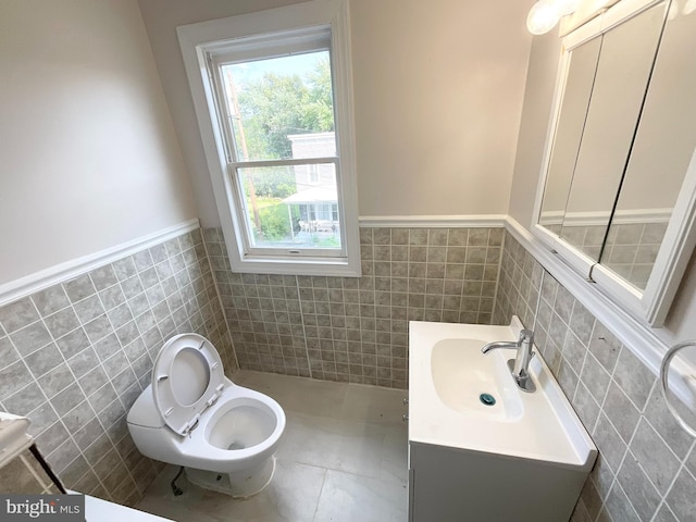 bathroom with tile walls, vanity, toilet, and tile patterned flooring