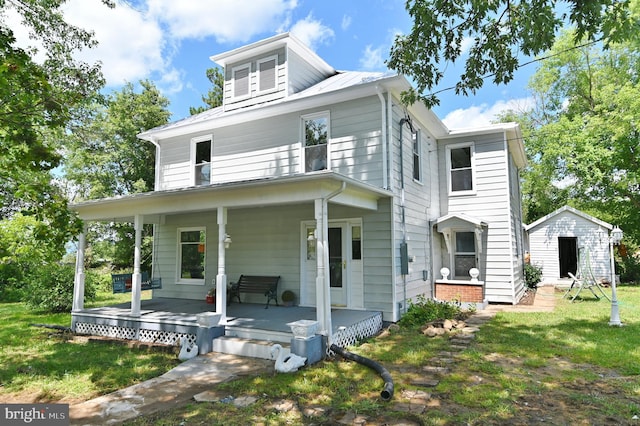 view of front facade featuring a front lawn, covered porch, and a storage unit