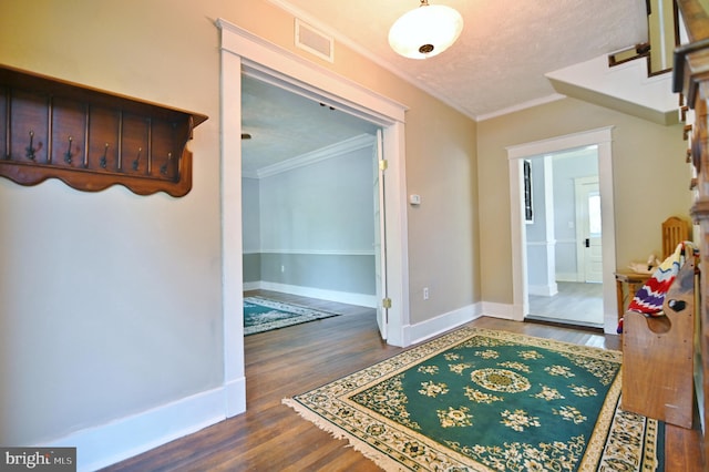 interior space with dark hardwood / wood-style flooring, ornamental molding, and a textured ceiling