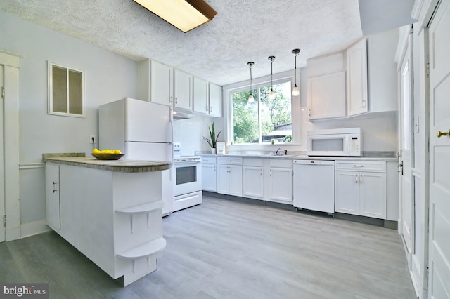 kitchen with white appliances, hanging light fixtures, light hardwood / wood-style floors, white cabinets, and a textured ceiling