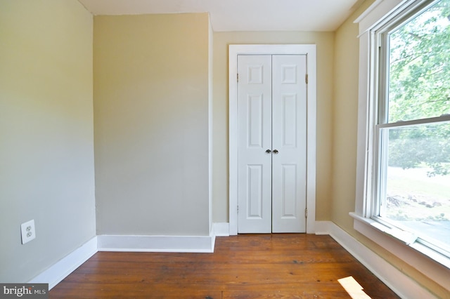 unfurnished bedroom with dark hardwood / wood-style floors and a closet