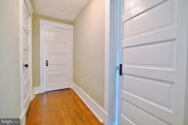 hallway featuring hardwood / wood-style floors and a textured ceiling