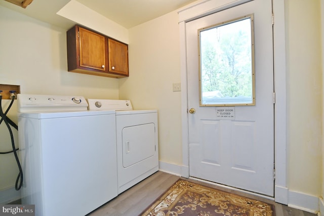 laundry area with independent washer and dryer, cabinets, and light hardwood / wood-style flooring