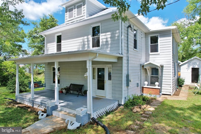 rear view of property with a porch and a shed