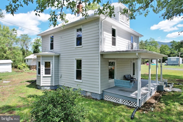 rear view of property with a porch, a deck, and a lawn