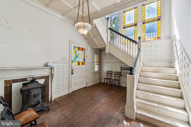 interior space with a wood stove, coffered ceiling, crown molding, and hardwood / wood-style flooring