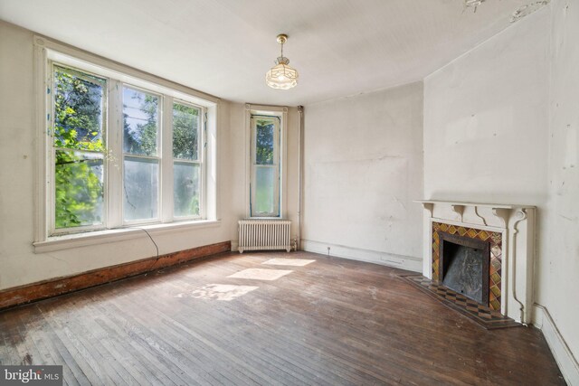 unfurnished living room featuring radiator heating unit and hardwood / wood-style flooring