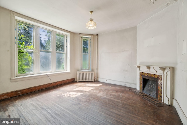 unfurnished living room featuring hardwood / wood-style flooring, a premium fireplace, and radiator