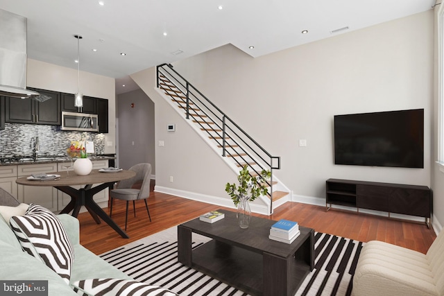 living room featuring baseboards, light wood finished floors, and stairs