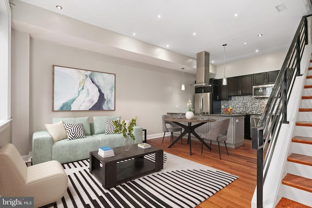 living room featuring recessed lighting, visible vents, light wood-style flooring, stairway, and baseboards