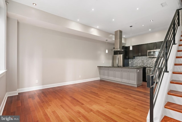 kitchen featuring stainless steel appliances, open floor plan, light wood-type flooring, island exhaust hood, and decorative light fixtures