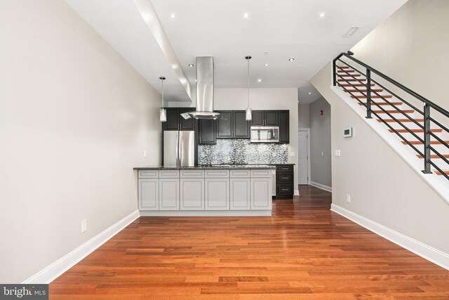 kitchen featuring tasteful backsplash, decorative light fixtures, hardwood / wood-style floors, and stainless steel appliances