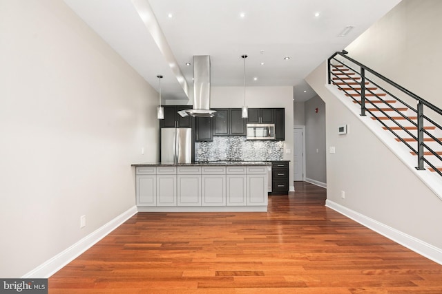 kitchen with island range hood, dark wood-type flooring, dark cabinets, decorative light fixtures, and stainless steel appliances