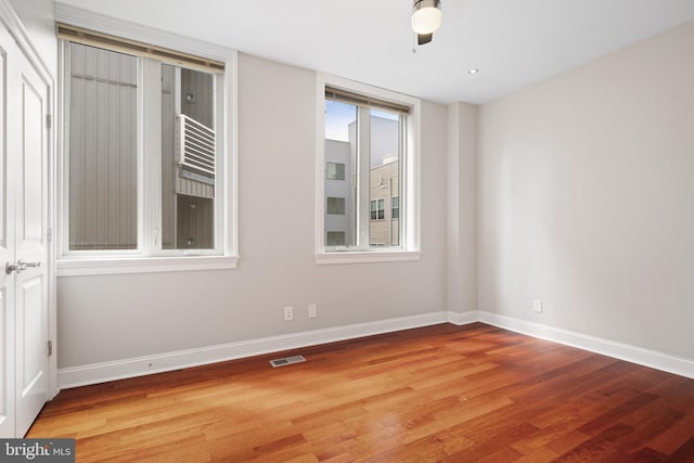 empty room featuring visible vents, baseboards, and wood finished floors