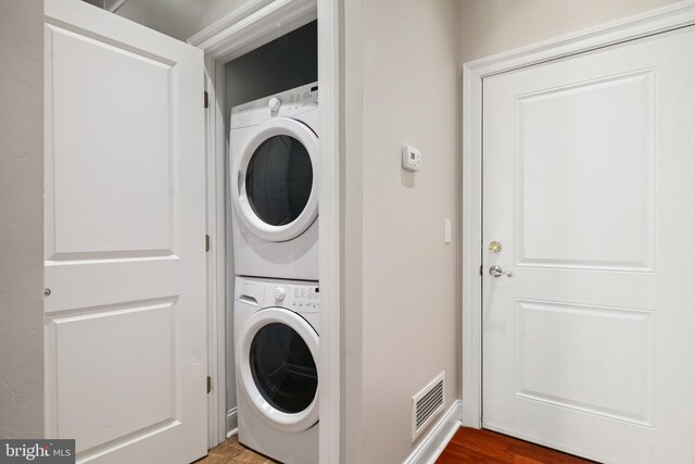 laundry area with hardwood / wood-style flooring and stacked washer and dryer