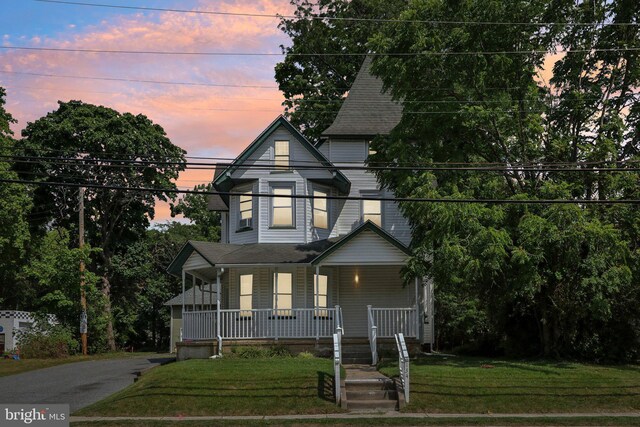 victorian-style house featuring a porch and a yard