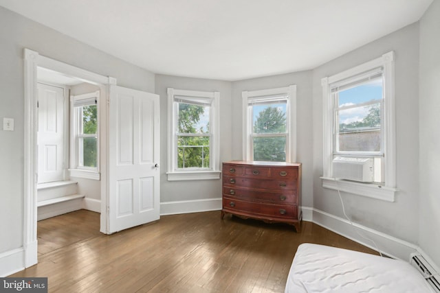 sitting room with a baseboard heating unit, wood-type flooring, cooling unit, and plenty of natural light