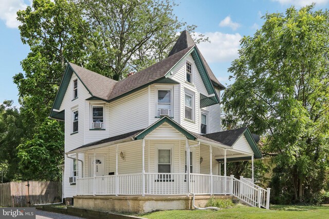 victorian-style house featuring covered porch and a front yard