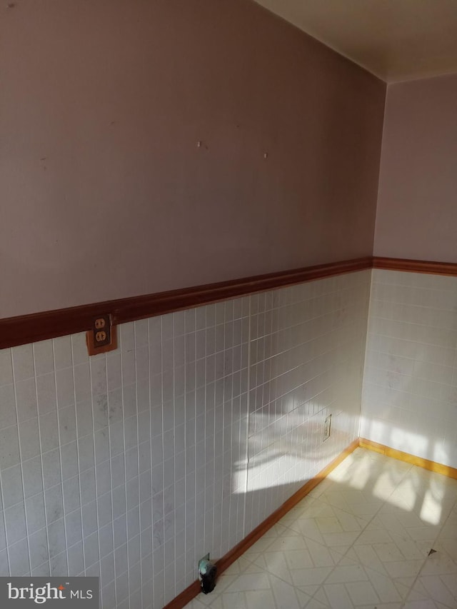 tiled spare room featuring tile walls